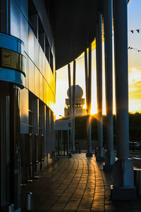 Footpath amidst buildings against sky at sunset