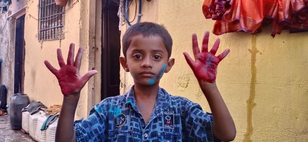 Portrait of boy with arms raised against wall