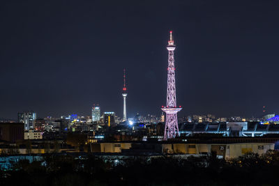Illuminated tower in city against sky at night
