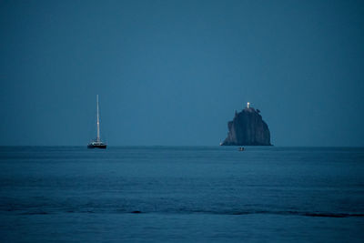 Sailboat sailing in sea against clear blue sky