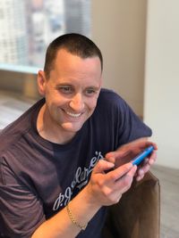 Portrait of happy man using mobile phone at home