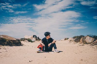 Full length of man sitting on land against sky