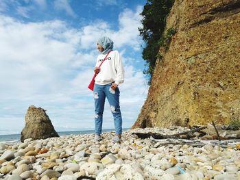 Full length of man standing on rock against sky