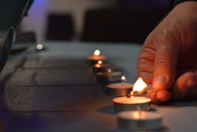 Cropped hand lighting candles on table