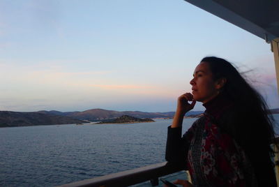 Side view of young woman looking at sea against sky