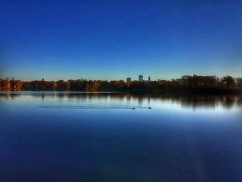 Calm lake against clear blue sky