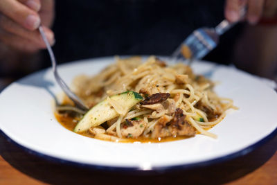Cropped image of person having noodles at table