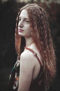 Beautiful young woman with curly hair looking away