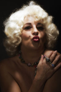 Close-up portrait of mature woman puckering over black background