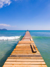 Pier over sea against clear blue sky