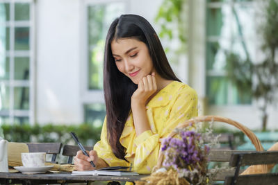 Beautiful woman sits writing on note book in garden