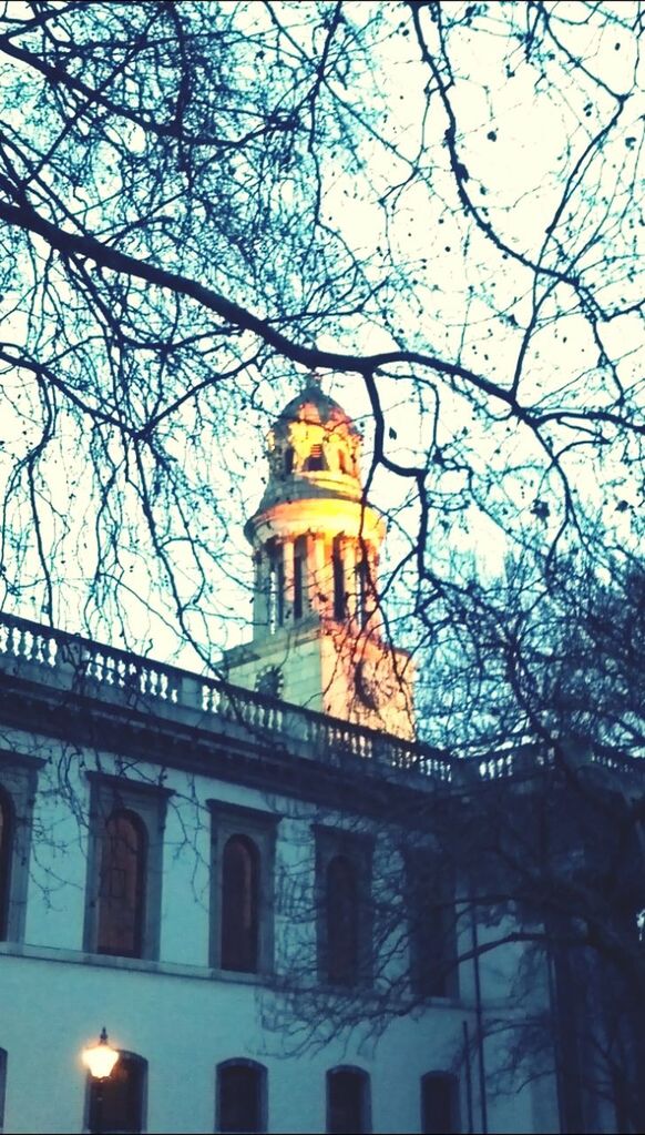 low angle view, architecture, building exterior, built structure, sky, religion, place of worship, spirituality, tree, bare tree, church, outdoors, blue, no people, city, clear sky, branch, statue, famous place