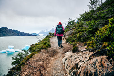 Rear view of woman walking on mountain against sky