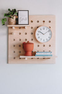 Close-up of clock with plants on wall 