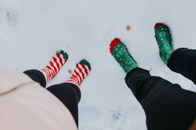 From above feet in socks of man and woman standing on snow ground