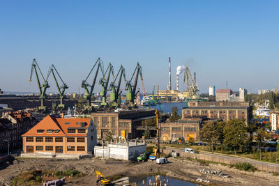 Cranes against buildings in city against clear sky