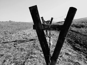 Old wooden post on field against clear sky