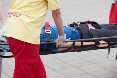 Midsection of man carrying patient on stretcher