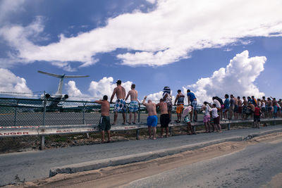 People on road against cloudy sky