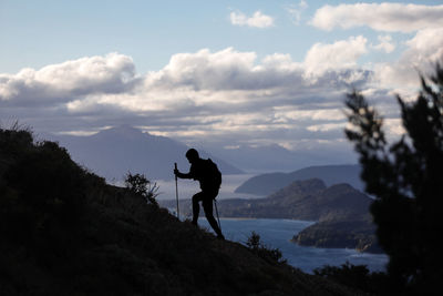 Rear view of man walking on mountain against sky