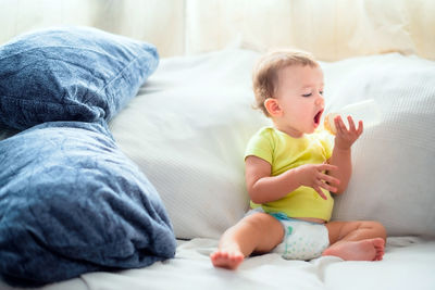 Cute baby girl sitting on bed at home