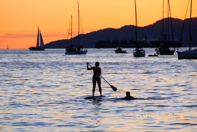 Silhouette man in boat sailing on sea against sky