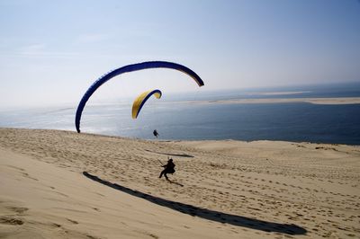 People enjoying on beach against sky