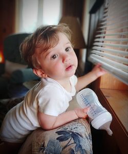 Cute baby girl sitting by window at home