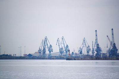 Cranes at commercial dock against clear sky