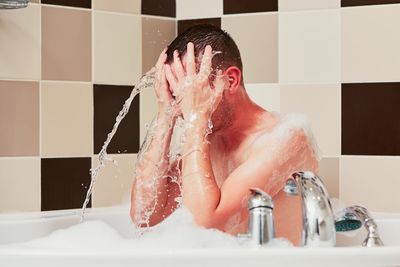 Full length of shirtless man in bathroom at home