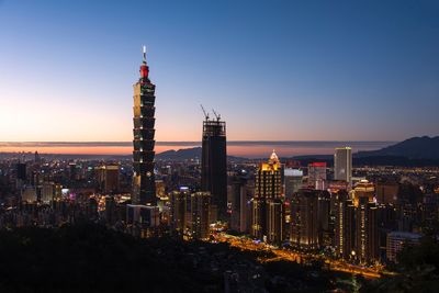 Illuminated cityscape against sky at night