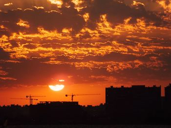 Silhouette buildings against dramatic sky during sunset