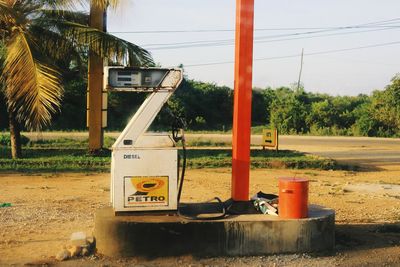 Information sign on field by road against sky