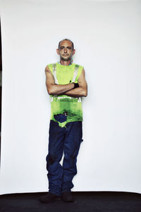 Serious worker standing with arms crossed against white backdrop