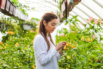 Young woman looking away while standing in plants