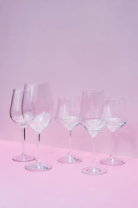 Various empty wine glasses on a pink background with space for text.