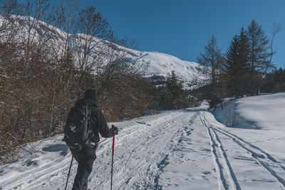 An unrecognizable male hiker wearing snowshoes walking in the french alps