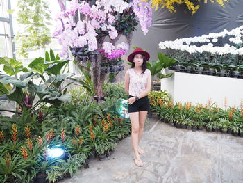 Portrait of smiling young woman standing against plants