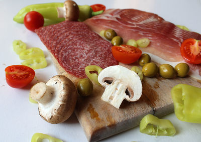Smoked meat,  mushrooms and vegetables arranged on a cutting board 