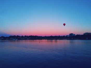 Hot air balloon over sea against clear sky during sunset