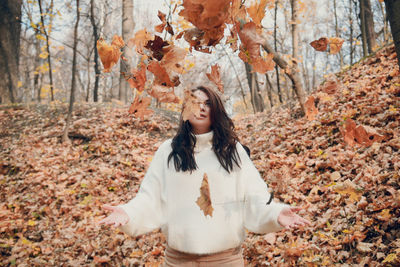 Young woman standing with autumn leaves in forest