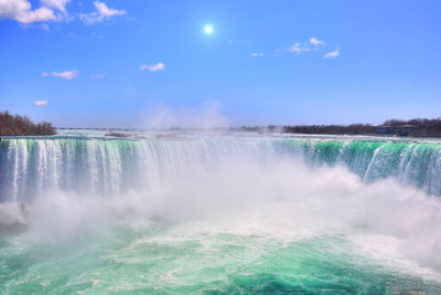 Scenic view of waterfall against sky