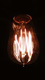 Close-up of illuminated light bulb against black background