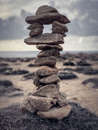 Close-up of stone stacked at beach against sky