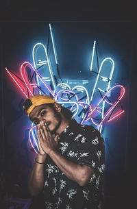 Young man standing against illuminated light painting