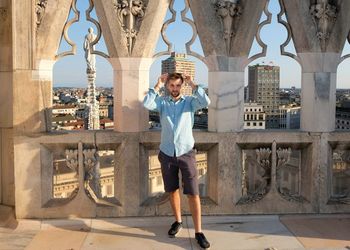 Portrait of man standing against railing in historic building