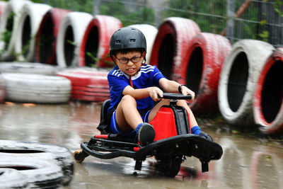 Boy riding vehicle on wet street