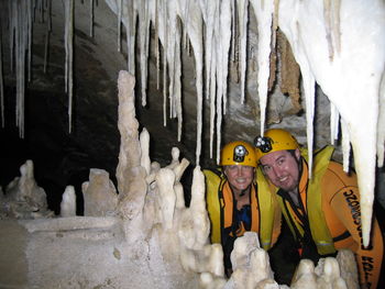 Portrait of happy friends standing by stalagmites and stalactites in cave