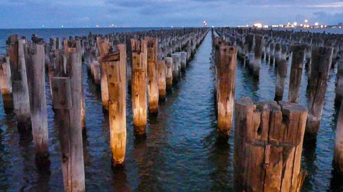 Panoramic view of wooden posts in sea against sky