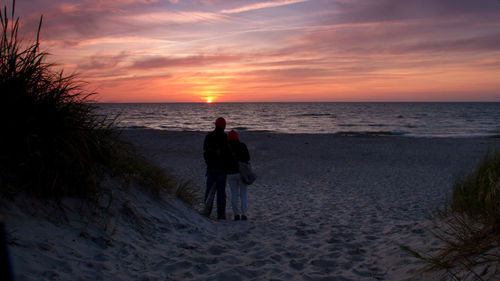 Silhouette man standing on beach against sky during sunset